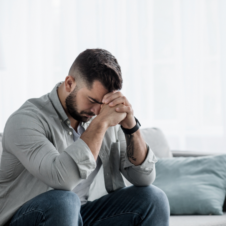 Man with hand on forehead, depicting stress and anxiety